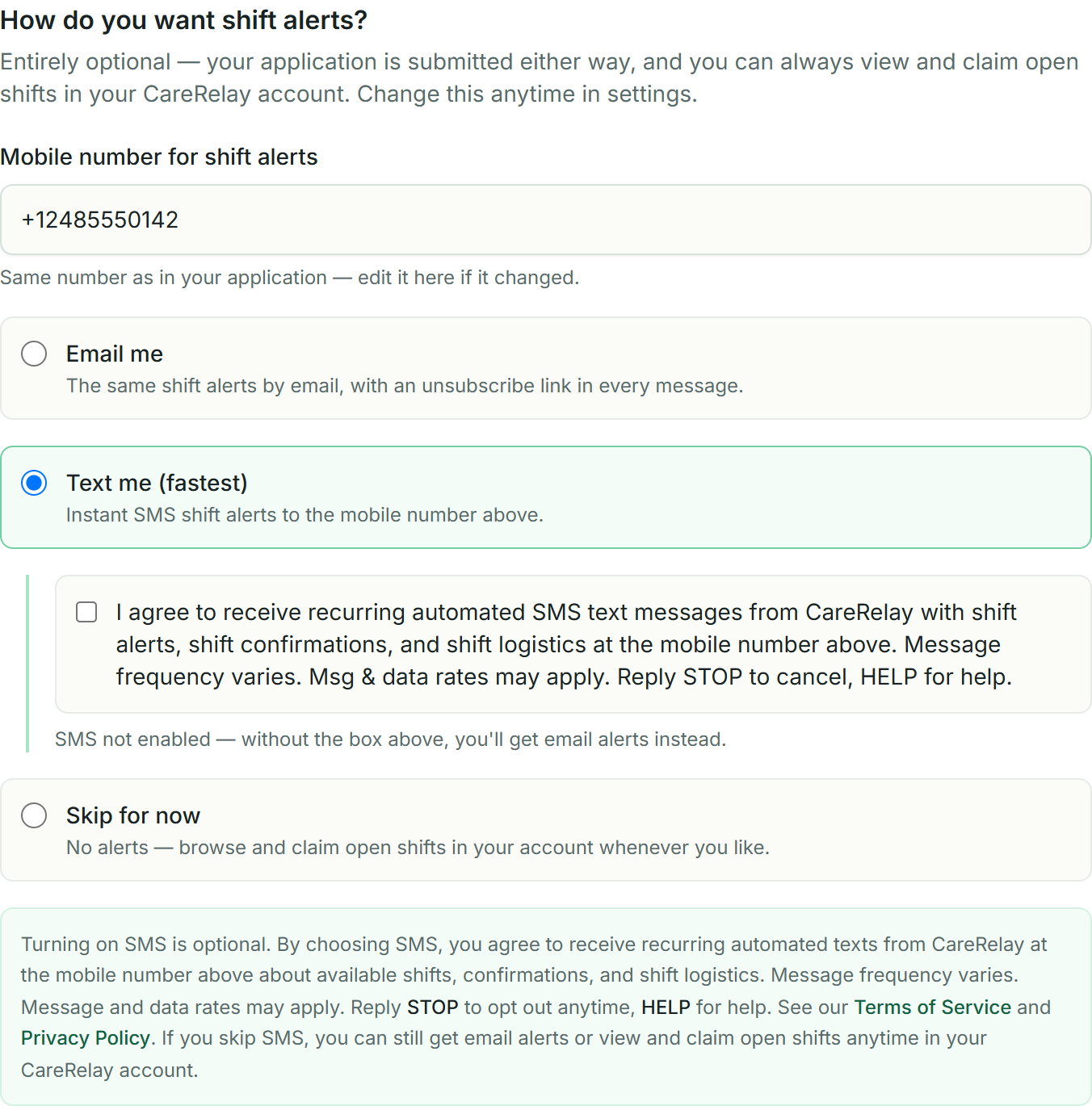 The CareRelay worker application notification step: the worker's editable mobile number, alert options with Email pre-selected by default, and — once Text me is chosen — a standalone unchecked consent checkbox above the full SMS disclosure with Terms of Service and Privacy Policy links.